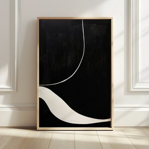 K&ouml;nnte beinhalten: Abstrakter Kunstdruck in einem Holzrahmen. Das Kunstwerk zeigt einen schwarzen Hintergrund mit einer wei&szlig;en, gebogenen Linie und einer wei&szlig;en, wellenf&ouml;rmigen Form. Das St&uuml;ck hat ein minimalistisches Design und eine moderne &Auml;sthetik.