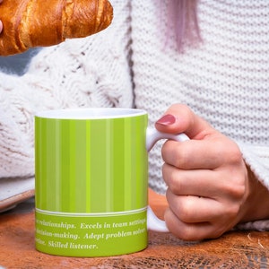 May include: A white ceramic mug with a green striped design and text that reads "Wintionships. Excels in team setting, decision-making. Adept problem solver. Skilled listener."