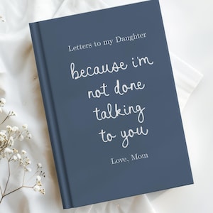 May include: A navy blue journal with the text "Letters to my Daughter" and the quote "because I'm not done talking to you" in white script. The journal is a hardcover book with a simple design.