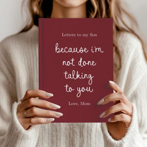 Peut inclure: Un journal de couleur bordeaux intitulé "Letters to my Son", tenu par une personne. La couverture porte l'inscription manuscrite "because I'm not done talking to you" et "Love, Mom". Un cadeau attentionné.