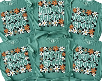May include: Six light green t-shirts featuring a black and white checkered square background with orange, white, and grey flowers. Each shirt displays text in a light green font: Kindergarten, First Grade, Second Grade, Third Grade, Fourth Grade, and Fifth Grade.