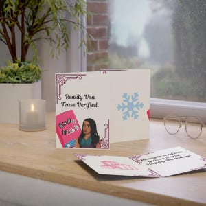 May include: Greeting card with the text "Reality Von Tease Verified." and an illustration of a woman and a book that says "Burn Book." The inside of the card reads "Receipts confirm you're iconic. Happy Birthday!" A blue snowflake is on the card.