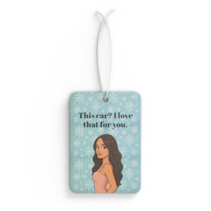 May include: Rectangular air freshener with a light blue background and a snowflake pattern. The air freshener features an illustration of a woman and the text "This car? I love that for you."