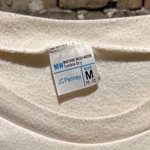 May include: White care label with the text "MW Machine Wash Warm Tumble Dry" and "JCPenney" with a size tag that says "Size M 10-12"