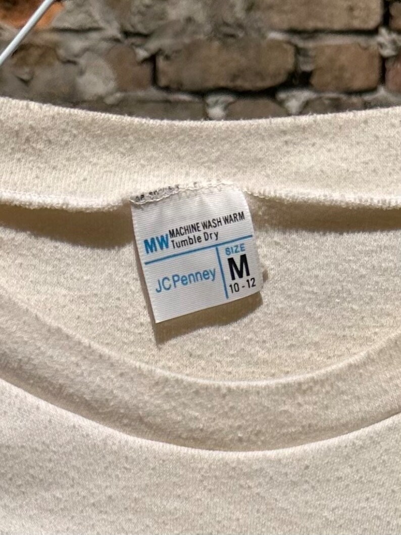 May include: White care label with the text "MW Machine Wash Warm Tumble Dry" and "JCPenney" with a size tag that says "Size M 10-12"