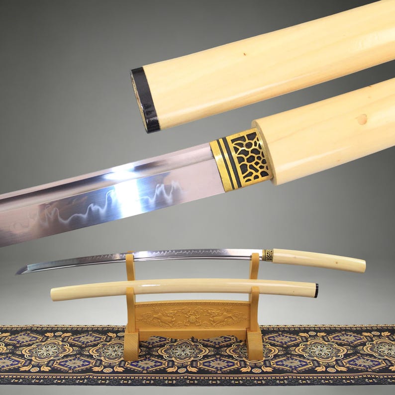May include: A Japanese katana sword with a curved steel blade featuring a wavy hamon line. The handle and scabbard are made of smooth, cream-colored material. A gold-colored metal collar with a black honeycomb pattern sits near the blade base.