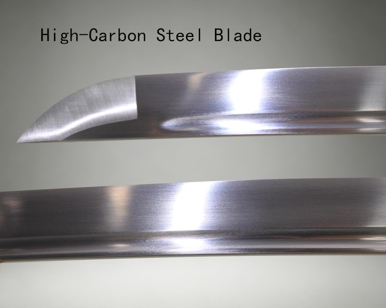 May include: A high-carbon steel blade with a polished, reflective metallic surface. The blade features a curved tip and a distinct edge line. The text "High-Carbon Steel Blade" is printed in black above the upper section of the metal blade.