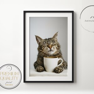 May include: A tabby cat with closed eyes sits on a white surface and holds a white mug with a brown liquid inside. The cat is smiling.