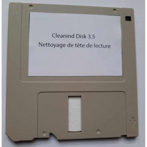 May include: A beige 3.5-inch floppy disk with a white label. The label reads "Cleanind Disk 3.5" and "Nettoyage de tête de lecture". The disk has a rectangular opening and several small holes.