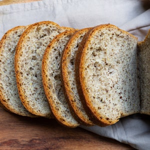 May include: Close-up of sliced bread with a grainy texture. The bread is light brown and has a slightly crispy crust.