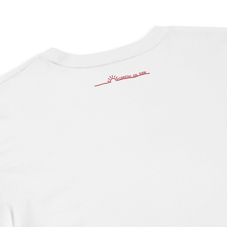 May include: White t-shirt with a red sun and the text "Coastal Sun Shop" on the back.