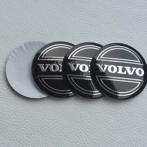 May include: Three black and silver Volvo emblem stickers with a glossy finish. The Volvo logo is displayed in silver lettering within a circular design. One sticker's backing is partially peeled.