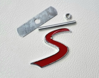 May include: A red metal letter 'S' with a chrome finish. The letter is attached to a metal plate with a screw and nut.