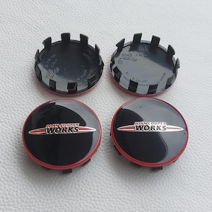 Pode incluir: Quatro tampas centrais de roda John Cooper Works pretas e vermelhas. As tampas têm uma base preta com uma borda vermelha e o logotipo John Cooper Works em prata e vermelho. A parte traseira das tampas é preta com uma série de abas.