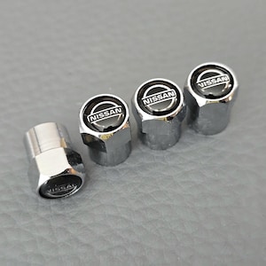 Puede incluir: Juego de cuatro tapones de válvula de neumático de cromo plateado con un logotipo de Nissan negro.