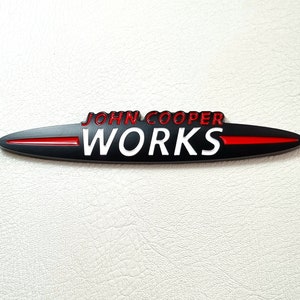 May include: Black and red John Cooper Works emblem with a white logo.
