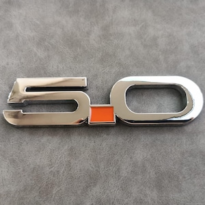 May include: Chrome 5.0 emblem with an orange square in the center.