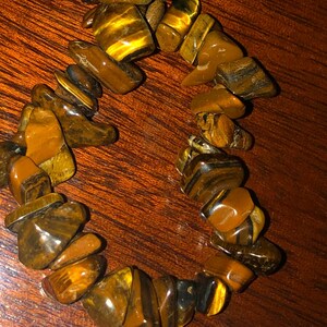 May include: A brown and gold tiger's eye stone bracelet with irregular shaped stones.