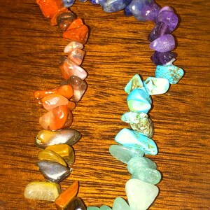 May include: A colorful gemstone bracelet featuring a variety of polished stones in shades of orange, yellow, green, blue, and purple. The stones are strung together to form a flexible bracelet, perfect for everyday wear.