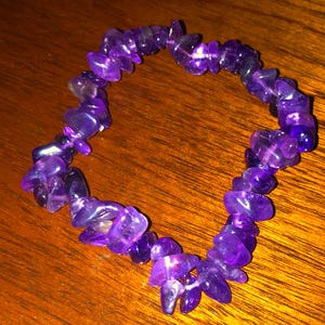 May include: A purple amethyst gemstone bracelet made of small, irregular shaped stones.