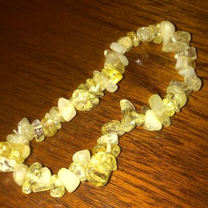 May include: A yellow and white chip stone bracelet. The bracelet is made of small, irregular shaped stones.