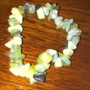 May include: A bracelet made of light green, white, and dark green stones. The stones are irregularly shaped and have a natural, polished finish.