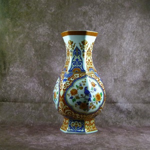 May include: A white porcelain vase with a geometric shape and intricate floral and bird designs in blue, orange, and gold.