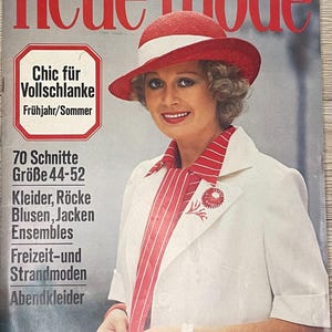 Può includere: Una copertina di rivista con una donna che indossa un cappello rosso e bianco e una giacca bianca con strisce rosse. La rivista si intitola "neue mode" e il testo "Chic für Vollschlanke" è visibile. La copertina della rivista include anche il testo "70 Schnitte Größe 44-52 Kleider, Röcke Blusen, Jacken Ensembles Freizeit-und Strandmoden Abendkleider".