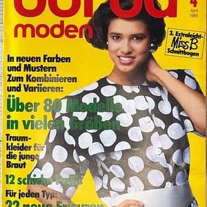 Puede incluir: Una portada de revista con una mujer que lleva un vestido de lunares negros y blancos con un cinturón blanco. La revista se titula "burda moden" y tiene el texto "Über 80 Modelle in vielen Größen" en la portada. La revista es de abril de 1985.