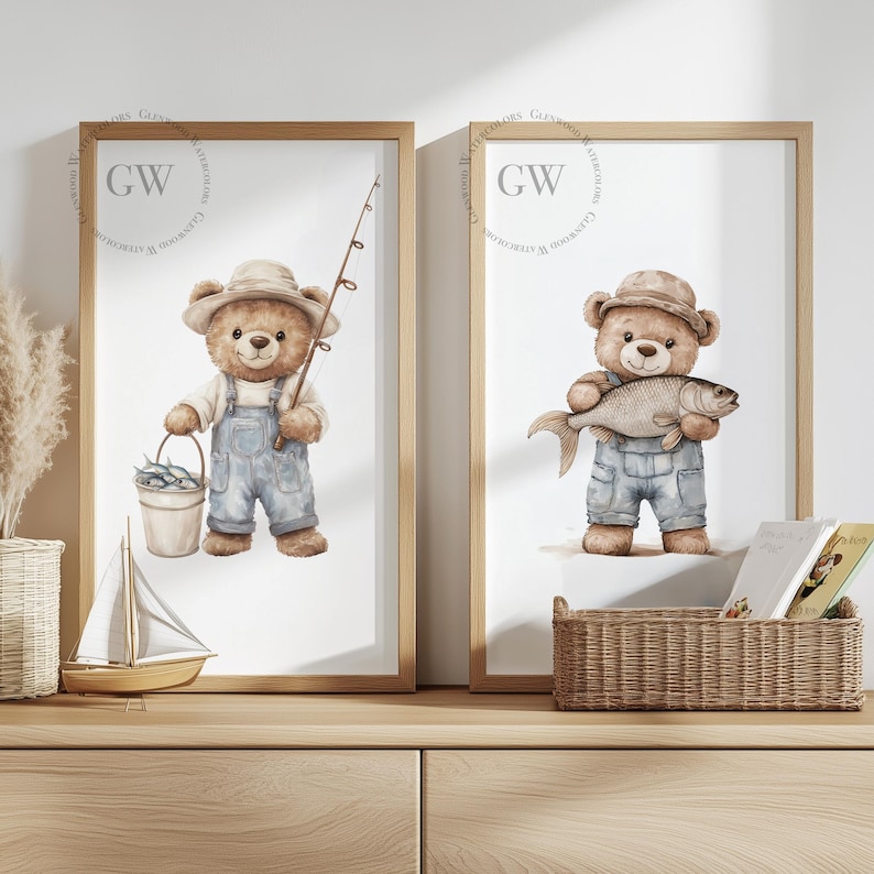 May include: Two framed prints of watercolor illustrations of teddy bears fishing. The bear on the left is holding a fishing rod and a bucket of fish. The bear on the right is holding a fish. Both bears are wearing overalls and hats. The prints are on a wooden shelf.