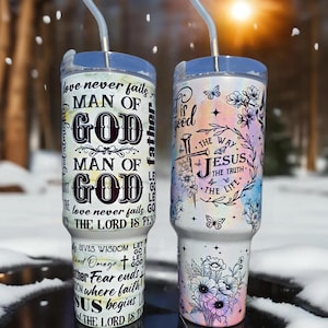 May include: Two white stainless steel tumblers with lids and straws. The tumbler on the left has black text that reads "love never fails - Man of God - Man of God - love never fails - The Lord is Peace". The tumbler on the right has a watercolor background with flowers and butterflies. The text reads "God is good - The way - Jesus - The truth - The life".