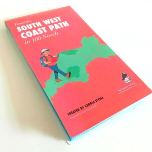 May include: A rectangular book with a bright coral cover featuring the text Read the SOUTH WEST COAST PATH in 100 Novels. The cover displays a green map illustration and a hiker reading a book. It includes the text CREATED BY CAROLE ESTALL.