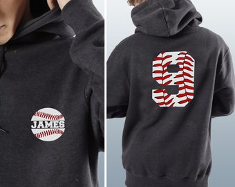 Puede incluir: Sudadera con capucha gris oscuro con diseño de béisbol. La parte delantera presenta un gráfico de béisbol con el nombre "JAMES". La parte trasera muestra un gran número "9" en un patrón de costura de béisbol. Una sudadera con capucha.