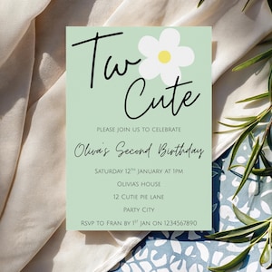 Puede incluir: Una tarjeta de invitación verde claro con las palabras "Two Cute" en escritura negra, una margarita blanca y detalles del evento. La invitación es para el Segundo Cumpleaños de Olivia, programado para el 12 de enero a la 1 PM.