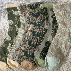 May include: Six pairs of green and beige patterned socks with different designs. The socks are made of a soft, comfortable material and have a ribbed texture.