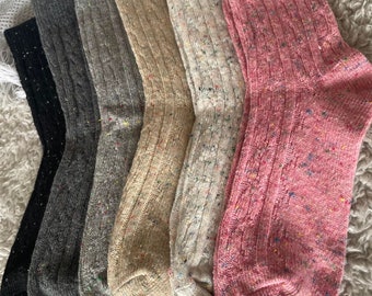 Puede incluir: Seis pares de calcetines coloridos con un patrón moteado. Los calcetines están hechos de un tejido suave y de punto y tienen un diseño de punto de cable. Los colores incluyen negro, gris, beige, blanco y rosa.