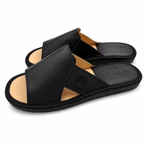 May include: A pair of black leather slide sandals with a textured pebble grain finish on the wide upper strap. The sandals feature a tan interior lining, a black footbed with the embossed text "basarim", and a black sole with stitched edges.