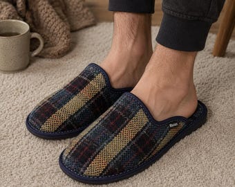 May include: A pair of plaid pattern slippers with a navy blue trim. The slippers have a dark color scheme with red, yellow, and blue accents. The slippers are on a light-colored carpet.