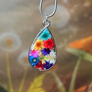 Colorful dried flowers in a teardrop shaped bezel pendant and on a silver necklace