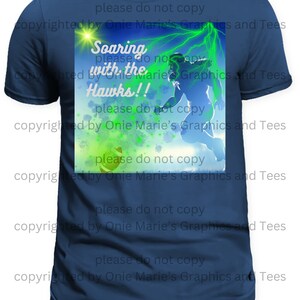 May include: A navy blue t-shirt with a green and blue graphic of a football player soaring through the air with the text "Soaring with the Hawks!" and the words "please do not copy copyrighted by Onie Marie's Graphics and Tees" repeated around the image.