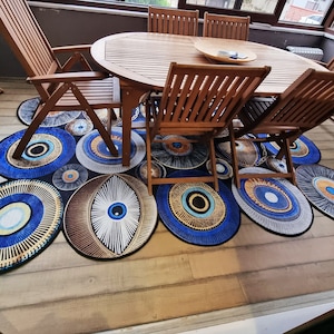 Puede incluir: Una mesa de comedor de madera con seis sillas, colocada sobre una alfombra con un patrón de ojo azul y blanco. La mesa es de madera oscura y tiene una forma rectangular. Las sillas también son de madera oscura y tienen un diseño sencillo.