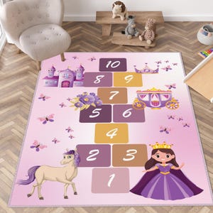 Può includere: Un tappeto gioco rosa per bambini con tema principessa. Il tappeto presenta un gioco della campana con numeri, una principessa, un cavallo, una carrozza, un castello e farfalle. Progettato per il gioco.