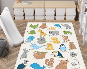 May include: A rectangular off-white children's rug featuring an alphabet of illustrated animals. Each animal is labeled with its name, such as "Alligator," "Bear," and "Zebra." The rug is placed on a wooden floor.
