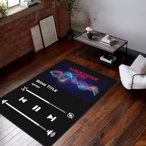 May include: Black and white rug with a music player design. The rug features a black background with white play and pause buttons, a volume control, and a song title and artist section. The top of the rug has a blue and purple abstract design with the text "Album Cover Here".
