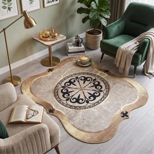 May include: An irregularly shaped area rug featuring a central circular medallion with a black floral motif on a beige marble-patterned background. The rug has a wide gold border with black fleur-de-lis accents at the four rounded corners.