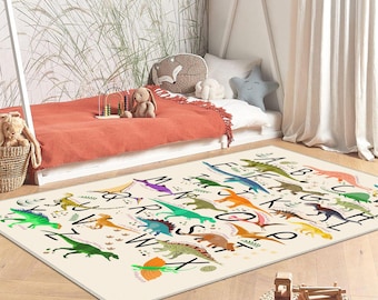May include: A rectangular rug with a cream background features colorful dinosaur illustrations and the alphabet. The dinosaurs are in shades of green, blue, orange, and yellow. Black letters are arranged around the dinosaurs. The rug is in a child's bedroom.