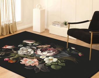 Può includere: Un tappeto rettangolare nero con una composizione floreale centrale di fiori bianchi, rosa e rosso scuro, foglie verdi e steli delicati. Il disegno è stampato su uno sfondo scuro, creando un contrasto con i fiori colorati.