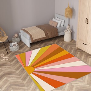 May include: A retro-style area rug with a sunburst design in shades of orange, pink, yellow, and brown. The rug is rectangular and placed on a wooden floor in a bedroom setting. The rug's dimensions are not visible.