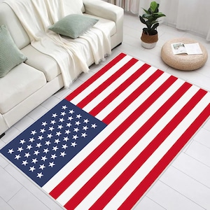 Puede incluir: Una alfombra de bandera americana roja, blanca y azul con un campo de estrellas azul en la esquina superior izquierda. La alfombra está colocada sobre un suelo de madera clara.