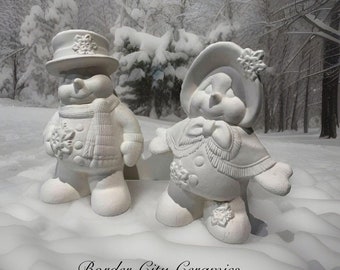 May include: Two white ceramic snowman figurines, one wearing a hat and the other wearing a bonnet, standing in a snowy landscape.  The text "Border City Ceramics" is visible at the bottom of the image.